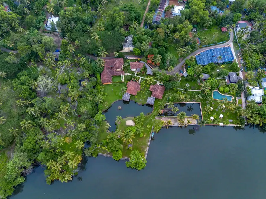 Ameya from above: tiled roofs among palms, the garden ponds and the pool at the edge of the lake