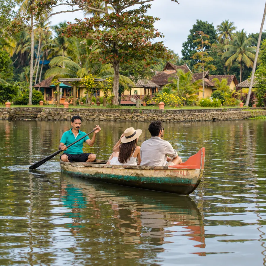 Guests in a wooden country boat gliding along the backwater past village cottages