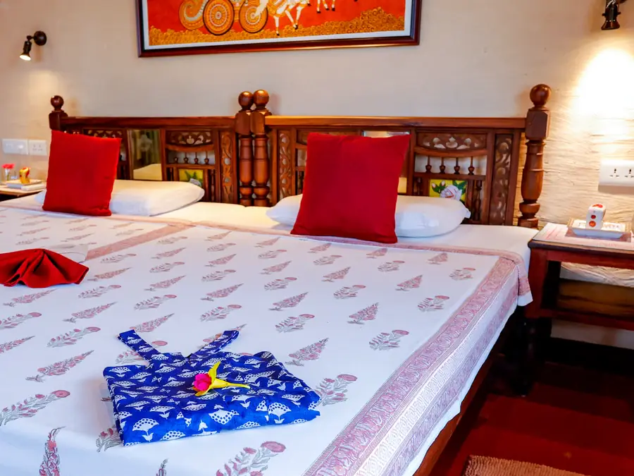 A cottage bedroom with a carved wooden headboard and block-printed linen