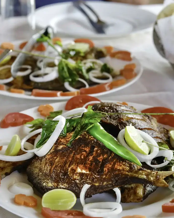 Karimeen, the pearl spot fish of the backwaters, fried Kerala style with green chilli, onion and lime